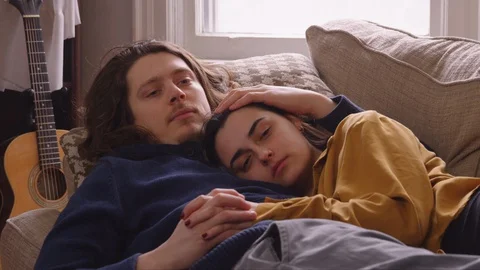 Couple lying down on a couch relaxing and watching TV. Stock Footage 129896896