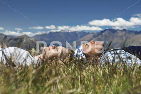 Couple Lying In Field Overlooking Hills Stock Photos