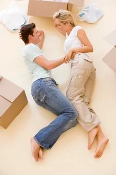 Couple lying on floor by open boxes in new home smiling Stock Photos