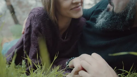 Couple lying on grass and looking at one another near to trees Stock Footage 275278357
