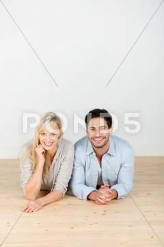 Couple lying on hardwood floor Stock Photos