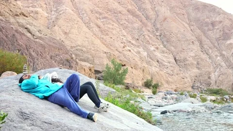 Couple lying on a rock by a river talking Stock Footage 196267661