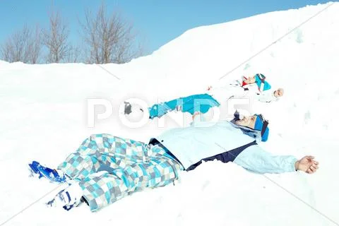 Couple lying on snow and enjoying good winter day Stock Photos