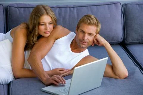 Couple lying on sofa with laptop Foto stock