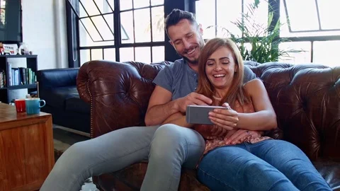 Couple lying on sofa looking at phone Stock Footage 76999541