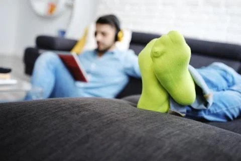 Couple Lying On Sofa With Tablet PC and Earphones Stock Photos