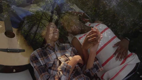 Couple lying under tree blanket, woman reaching smartphone opening tech gallery Stock Footage 313094417