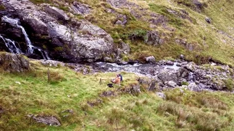 Couple make a video on the shore of a waterfall in Lake District Stock Footage 220357216