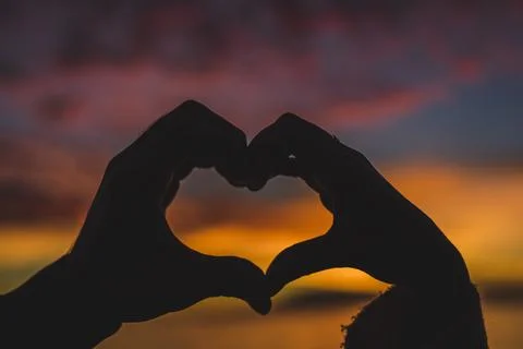 Couple making heart shape from hands sea shore Stock Photos