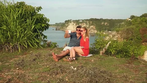 Couple making selfie on edge of Bali shore cliff, long shot 動画素材 77955604