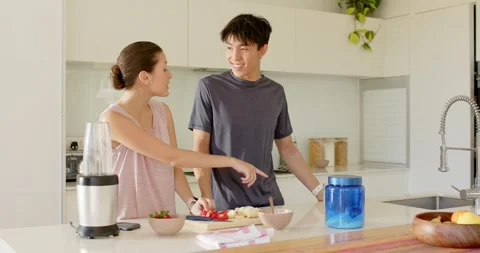 Couple making smoothie at kitchen island, woman pointing blue jar causing man Stock Footage 344333807