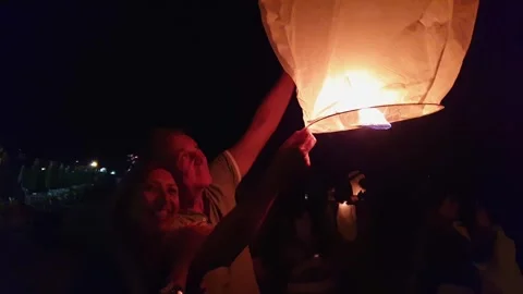 Couple making wish with fire sky lanterns on beach Stock Footage 279907405