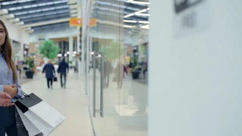 Couple in the mall is standing in front of the storefront and picks the goods Stock Footage 96749849