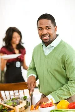 Couple: man working on dinner preparation Stock Photos