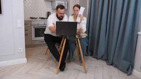 Couple managing finances at home using laptop and notebook Stock Footage 317443031