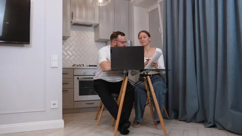 Couple managing finances at home using laptop and notebook Vidéo 317443052