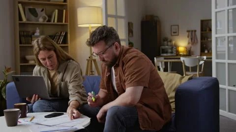 Couple Managing Finances with Man Sorting Documents and using Highlighter Stock Footage 327681855