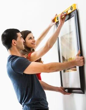 Couple measuring picture frame on wall Stock Photos