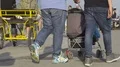 Couple of men pushing stroller while taking walk along waterfront on sunny day HD Footage