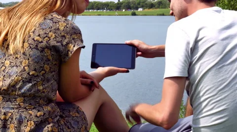 Couple with mini tablet by lake Stockbeeldmateriaal 40615008
