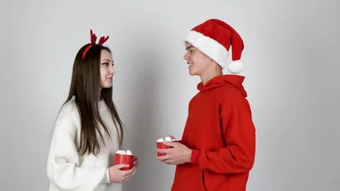 Couple is a moment while holding mugs of a hot drink, dressed in Christmas Stock Footage 319825238