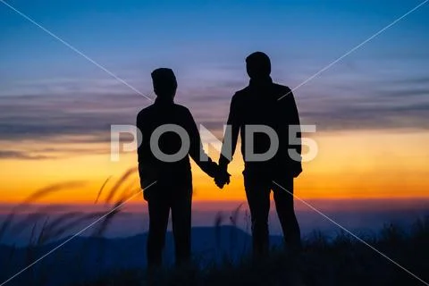 The couple on the mountain enjoying a picturesque sunrise background Stock Photos