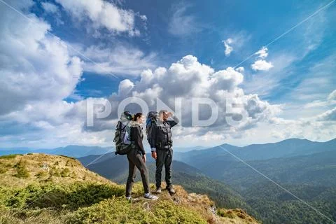 The couple on the mountain on the picturesque cloudscape background Stock Photos