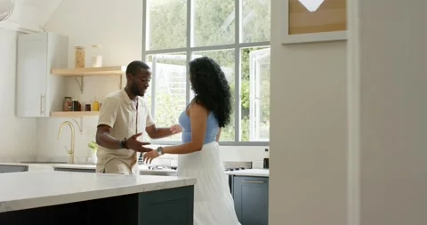 Couple near kitchen window, man speaking, woman in blue top turning, exchanging Stock Footage 336437850