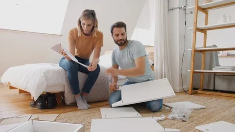 Couple In New Home Putting Together Self Assembly Furniture Stock Footage