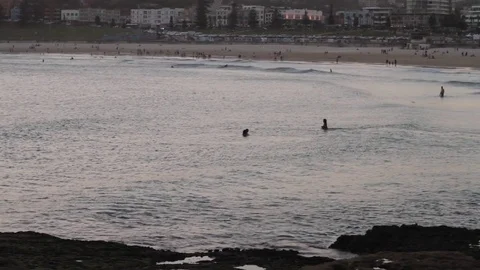 Couple in Ocean with beach bay in background at Sunset. Wide Shot. Stock Footage 85295748