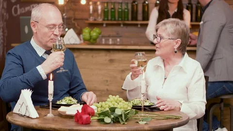 Couple of old people on a date clinking glasses and enjoy wine Stock Footage 106455153