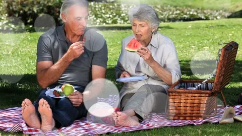 Couple opening box, placing plates, eating fruit on blanket bokeh floating for Stock Footage 333803631