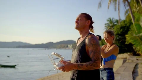 Couple operating remote of quadcopter drone and photographing on beach Stock Footage 74778587