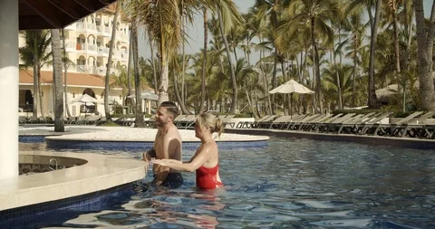 Couple Orders Drinks at Swim Up Bar, Tropical Resort Pool Stock Footage 112412786
