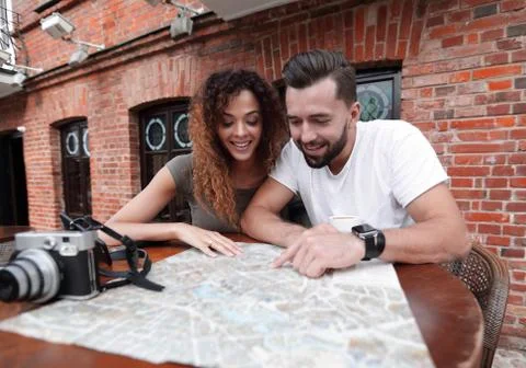 Couple in an outdoor cafe using map and planning itinerary Fotos Stock