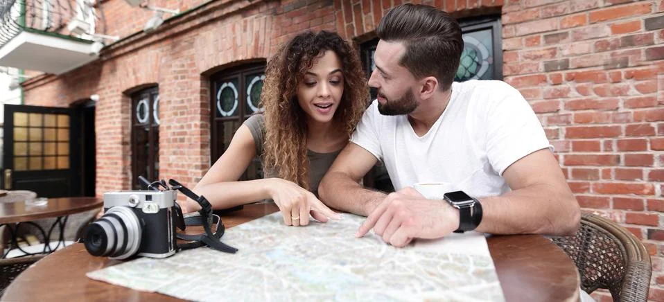 Couple in an outdoor cafe using map and planning itinerary Fotos Stock