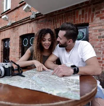 Couple in an outdoor cafe using map and planning itinerary Fotos Stock
