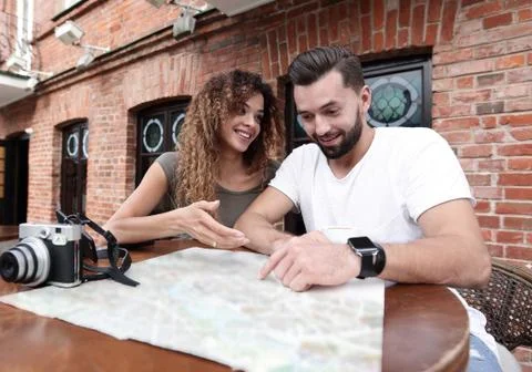 Couple in an outdoor cafe using map and planning itinerary Fotos Stock