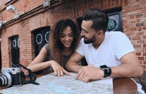Couple in an outdoor cafe using map and planning itinerary Fotos Stock