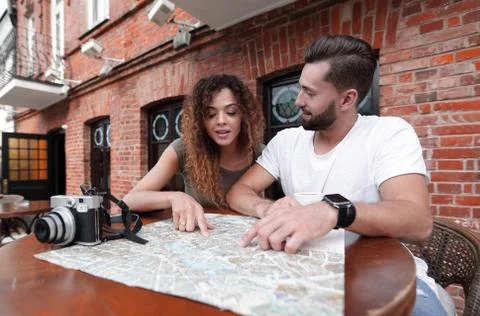Couple in an outdoor cafe using map and planning itinerary Fotos Stock