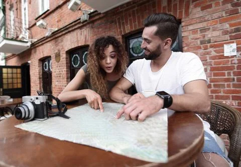 Couple in an outdoor cafe using map and planning itinerary Fotos Stock