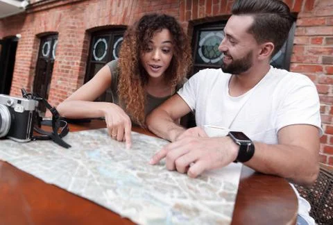 Couple in an outdoor cafe using map and planning itinerary Fotos Stock