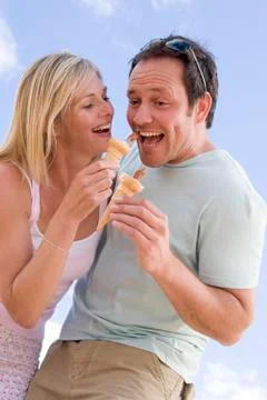 Couple outdoors eating ice cream and smiling Stock Photos