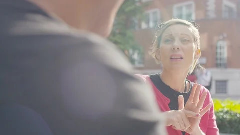 Couple outdoors engaged in conversation using sign language to arrange lunch Stock Footage 114005120