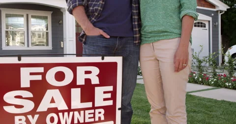 Couple Outside Home With For Sale Sign Shot On R3D Stock Footage