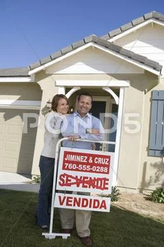 Couple Outside Home With Sold Sign