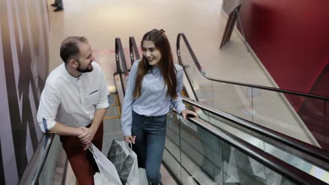 Couple with packages on the escalator. shopping theme Stock Footage 98306673