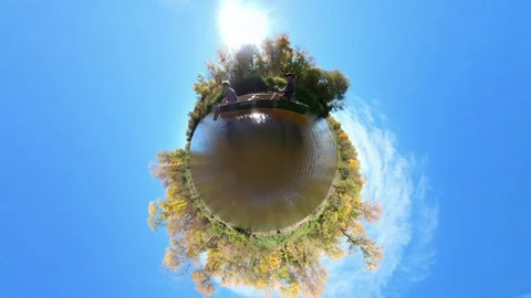 Couple paddling canoe in tiny planet clip on autumn river. Blue sky Stock Footage 287222711