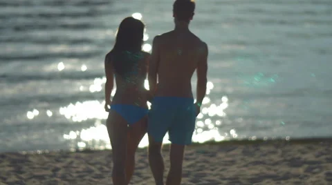 The couple (pair) walk on the beach and hug by the bright sunlight reflection 库存影片 56090653