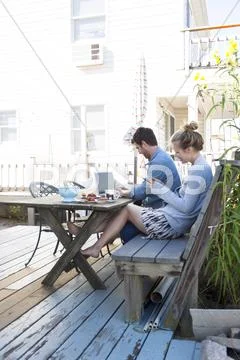 Couple On Patio With Laptop And Mobile, Breezy Point, Queens, New York, Usa
